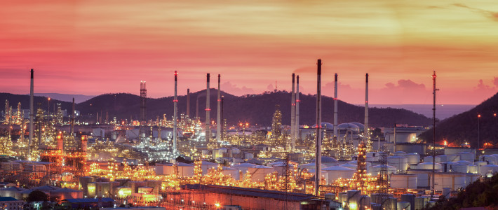Oil refinery with tube and oil tank along twilight sky